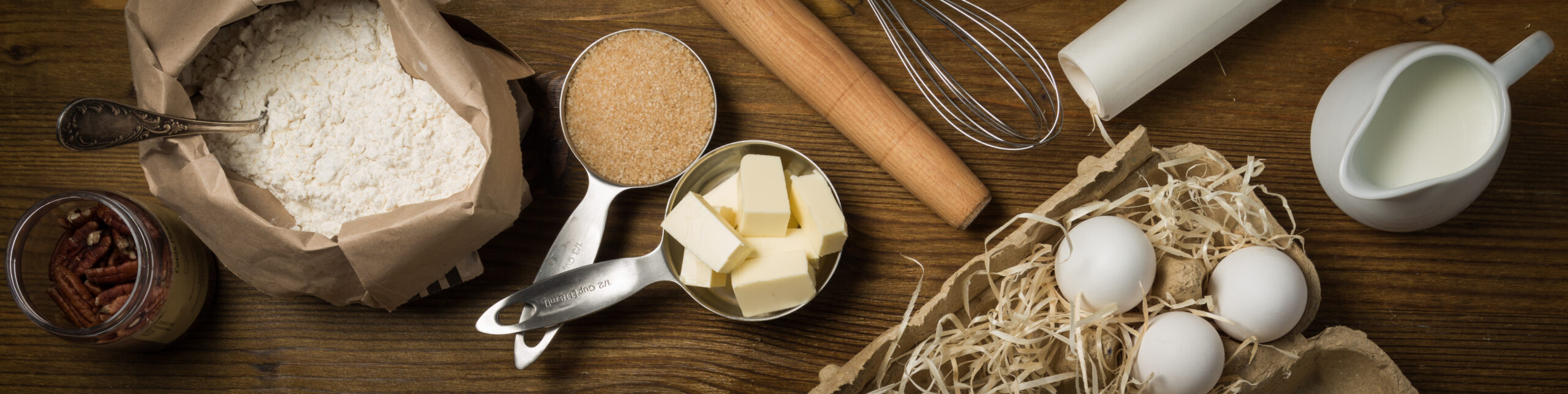 Baking ingredients in measuring cups, rustic wood background